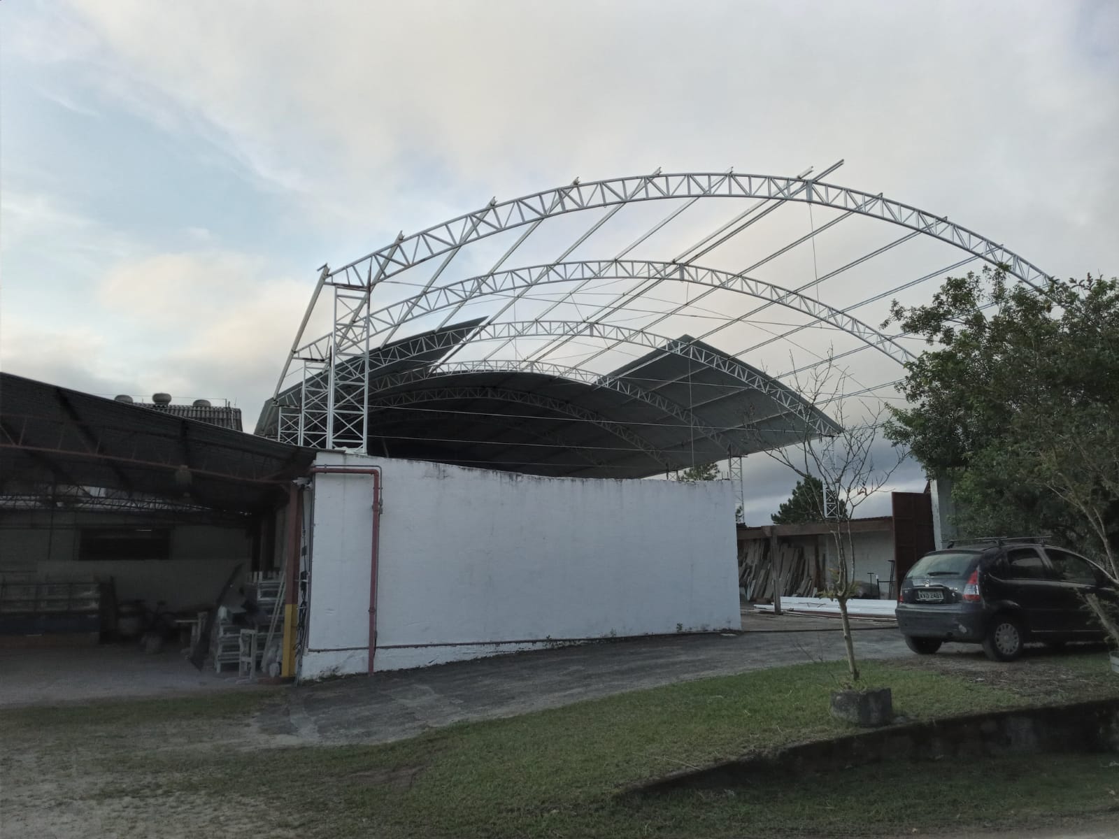 Cobertura metálica em arco tipo treliça sobre galpão